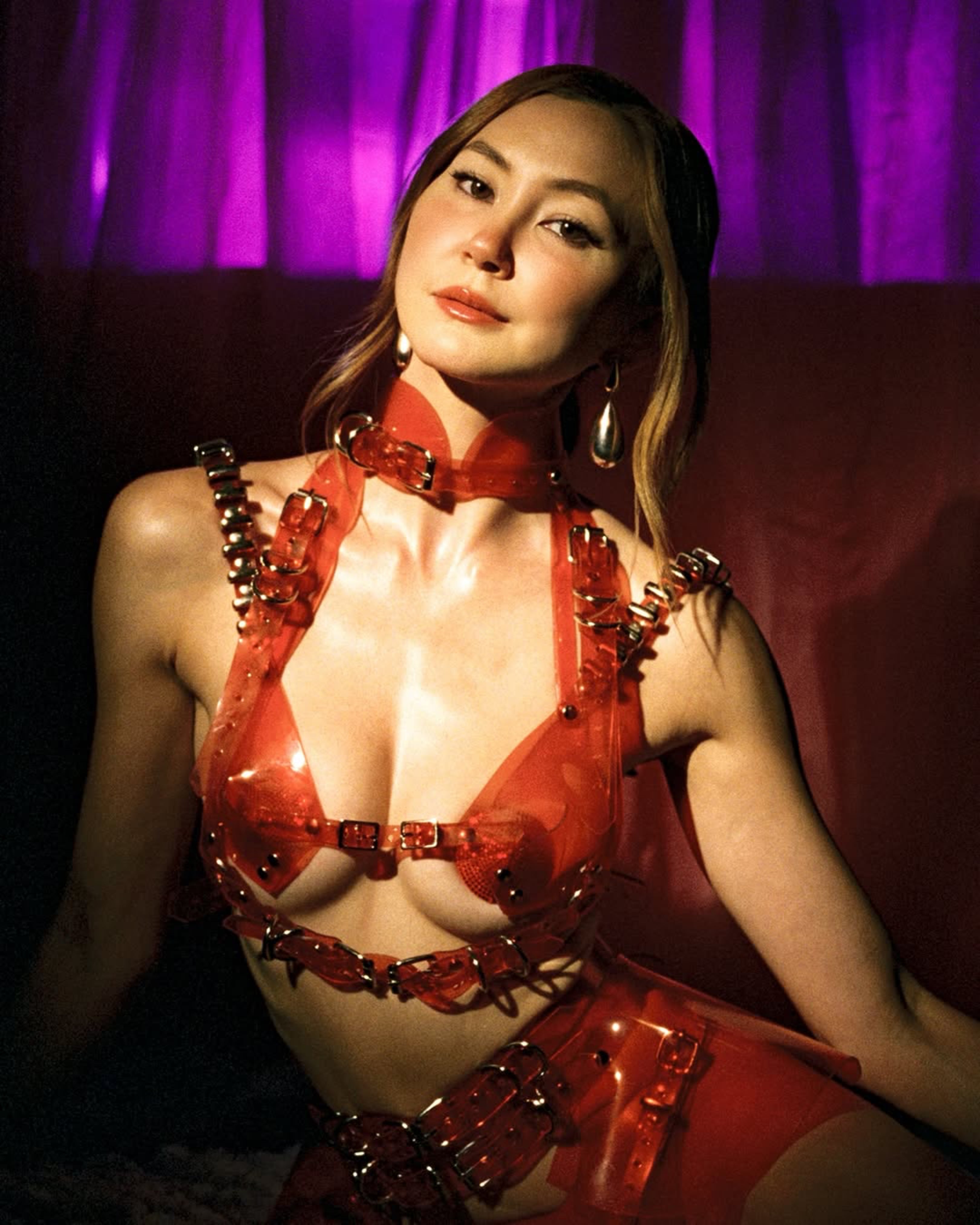 Kimiko Glen wearing  ATÉLIER JIVOMIR vegan vinyl lingerie set clear red harness mini ring
